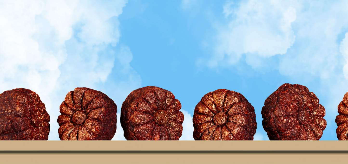 Line of brown date mithai bite on a beige surface with a blue sky background