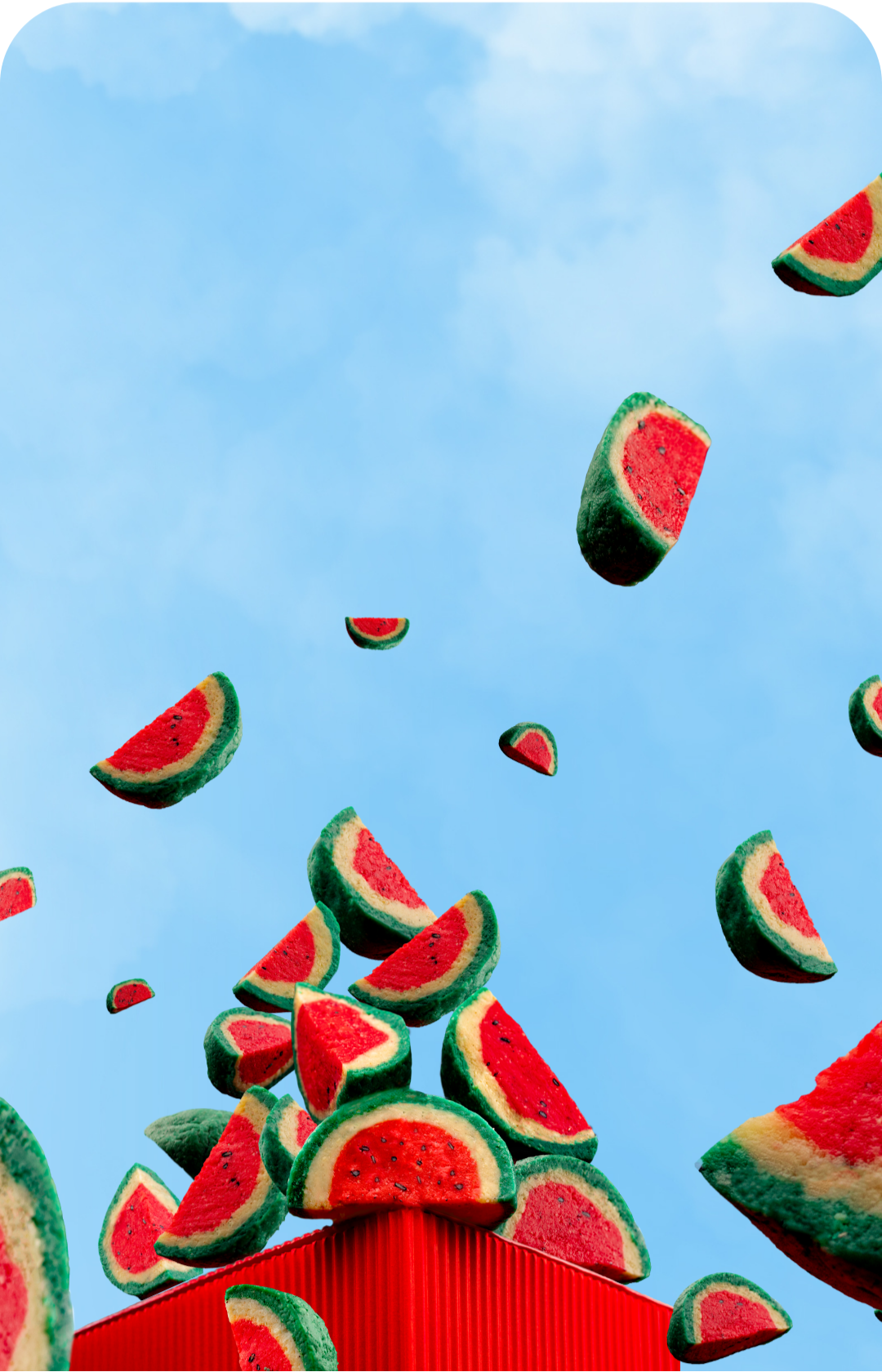 Slices of watermelon falling against a blue sky